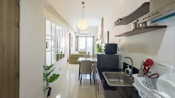 Una cocina moderna con lavamanos, refrigerador y comedor con sillas y mesa.