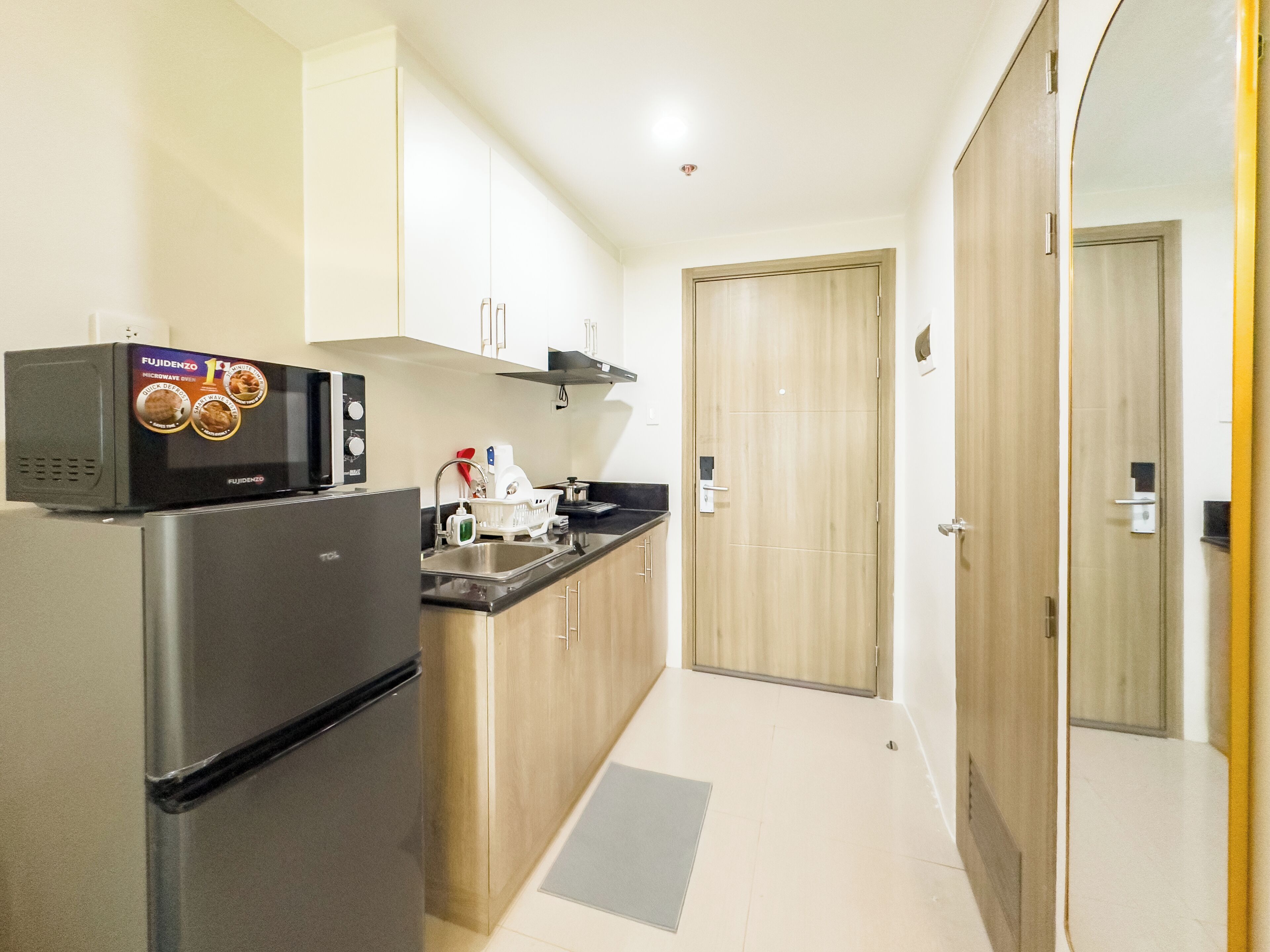 Una cocina compacta equipada con refrigerador, microondas y pileta.