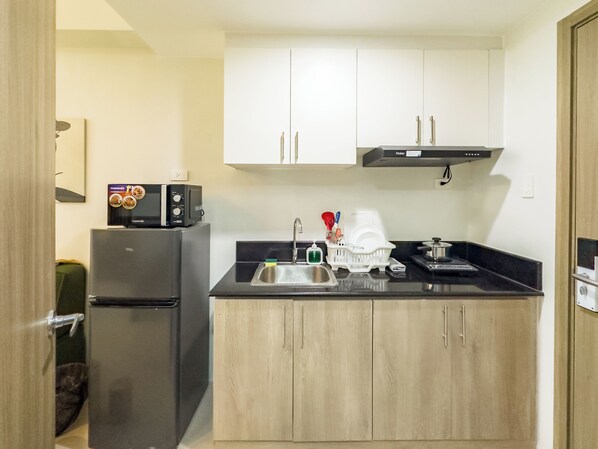 Una cocina pequeña equipada con refrigerador, microondas, pileta y alacenas.