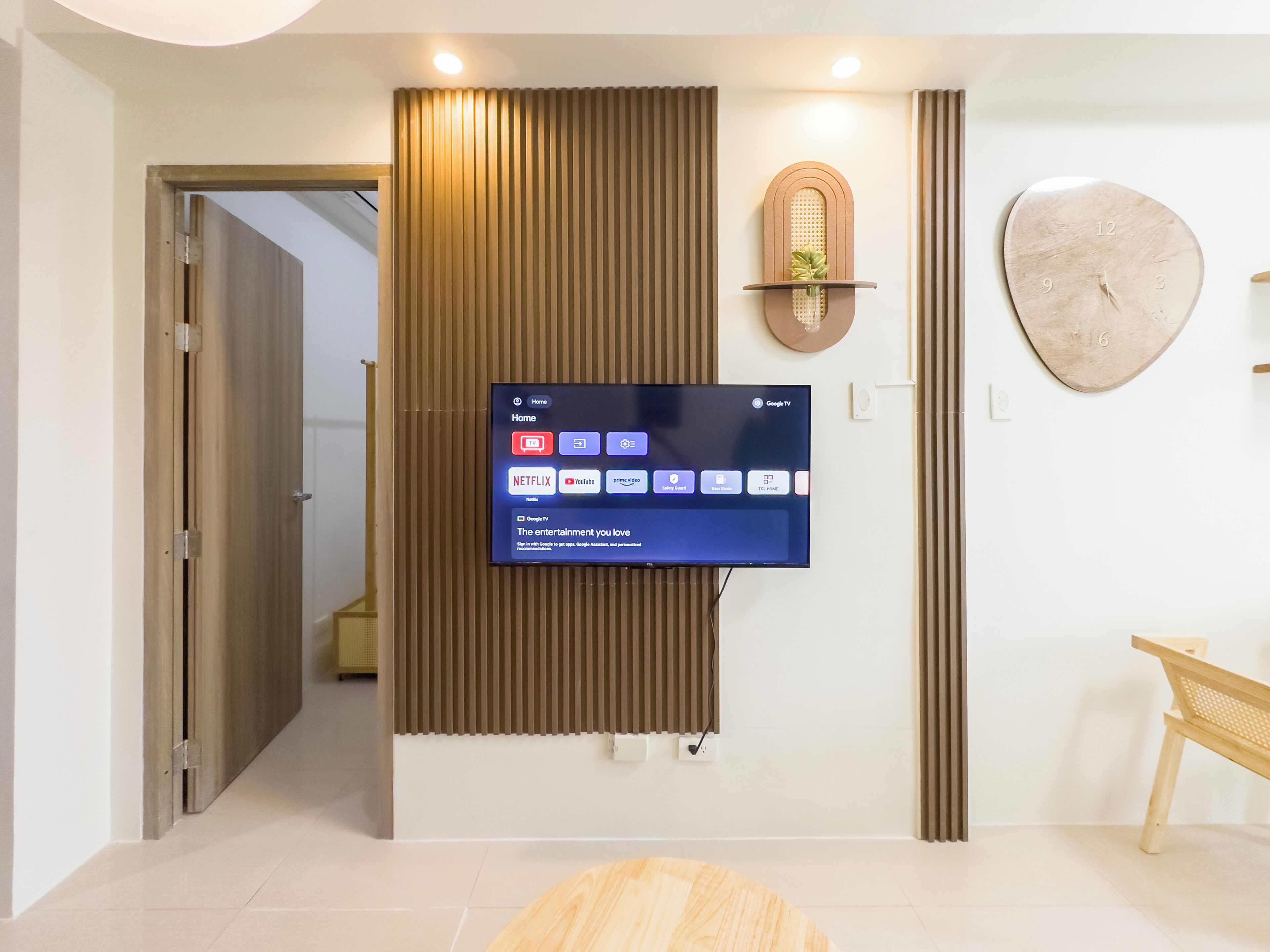 Een moderne woonkamer met een wandgemonteerde flatscreen-tv die een startscherm toont met verschillende streamingdiensten.