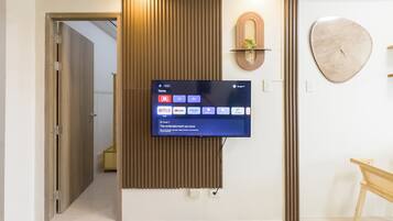 Een moderne woonkamer met een wandgemonteerde flatscreen-tv die een startscherm toont met verschillende streamingdiensten.