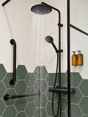 Une douche dotée de plusieurs jets et d  ’un pommeau de douche à main, installée sur un mur recouvert de carreaux hexagonaux de deux couleurs différentes.