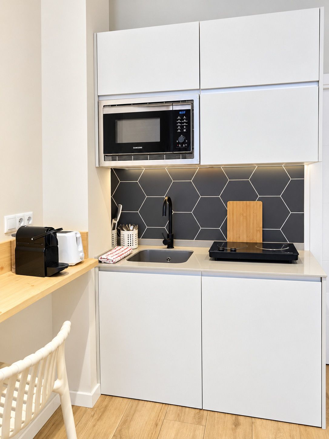 A compact kitchen with a microwave, sink, and a toaster.