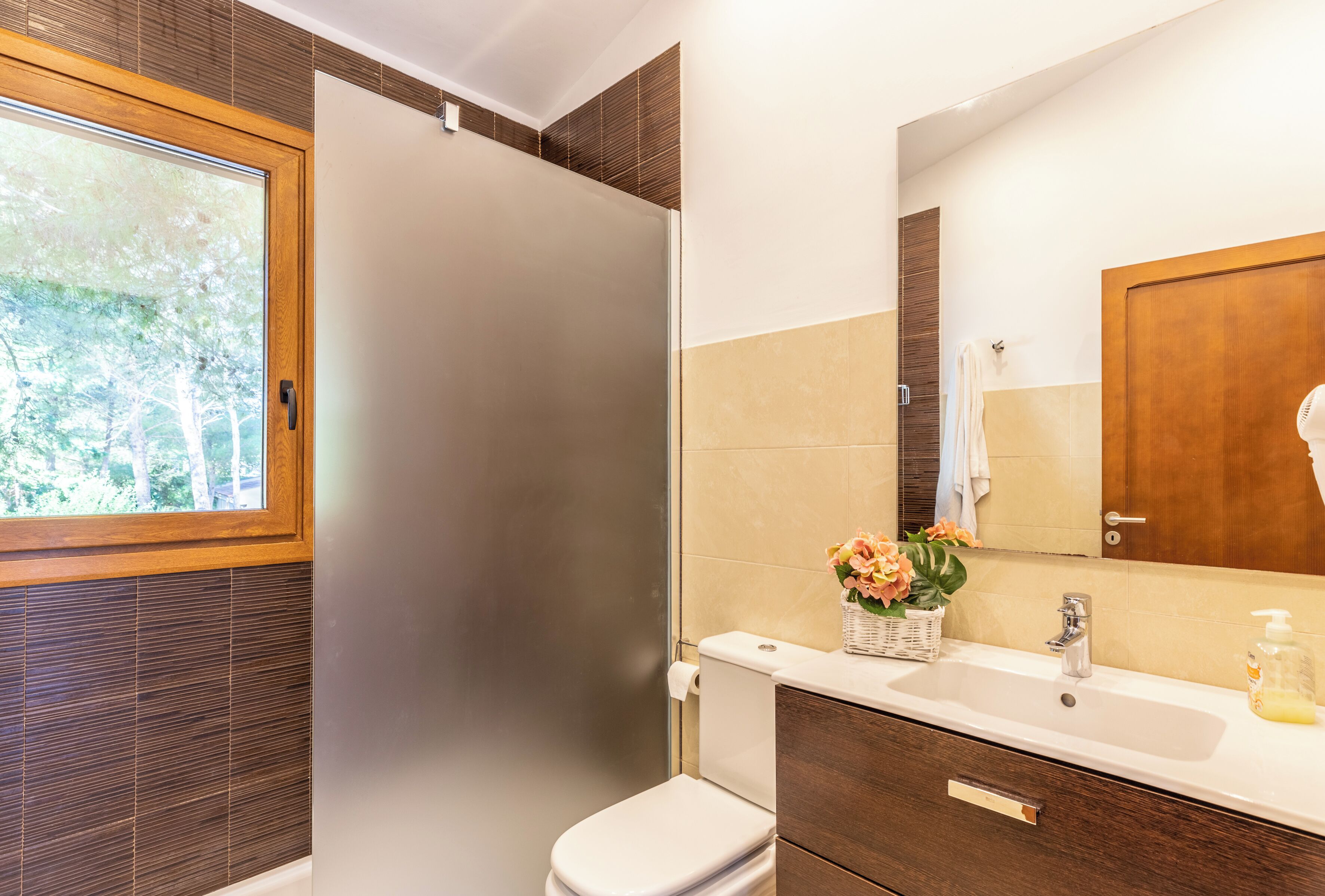 Une salle de bain moderne équipée d’une douche, de toilettes, d’un lavabo et d’un grand miroir.
