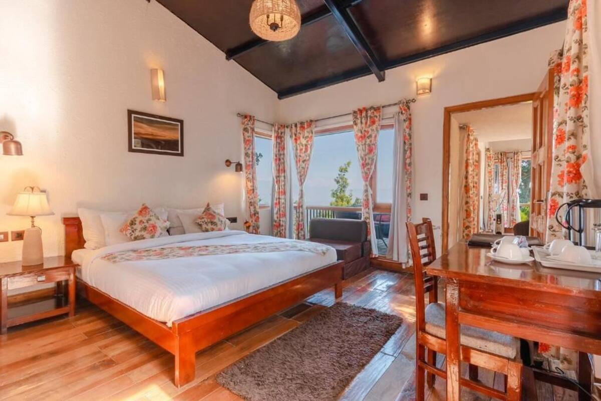 A bedroom with a wooden bed, a nightstand, a table with a tea set, and a balcony with curtains.