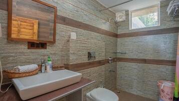 Un baño con un lavamanos grande, un inodoro y una zona de ducha.