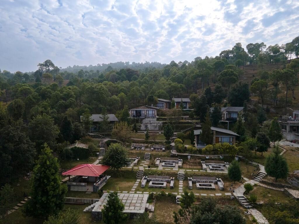 Ein Friedhof mit in Reihen angeordneten Grabsteinen, umgeben von Bäumen und einigen Gebäuden.