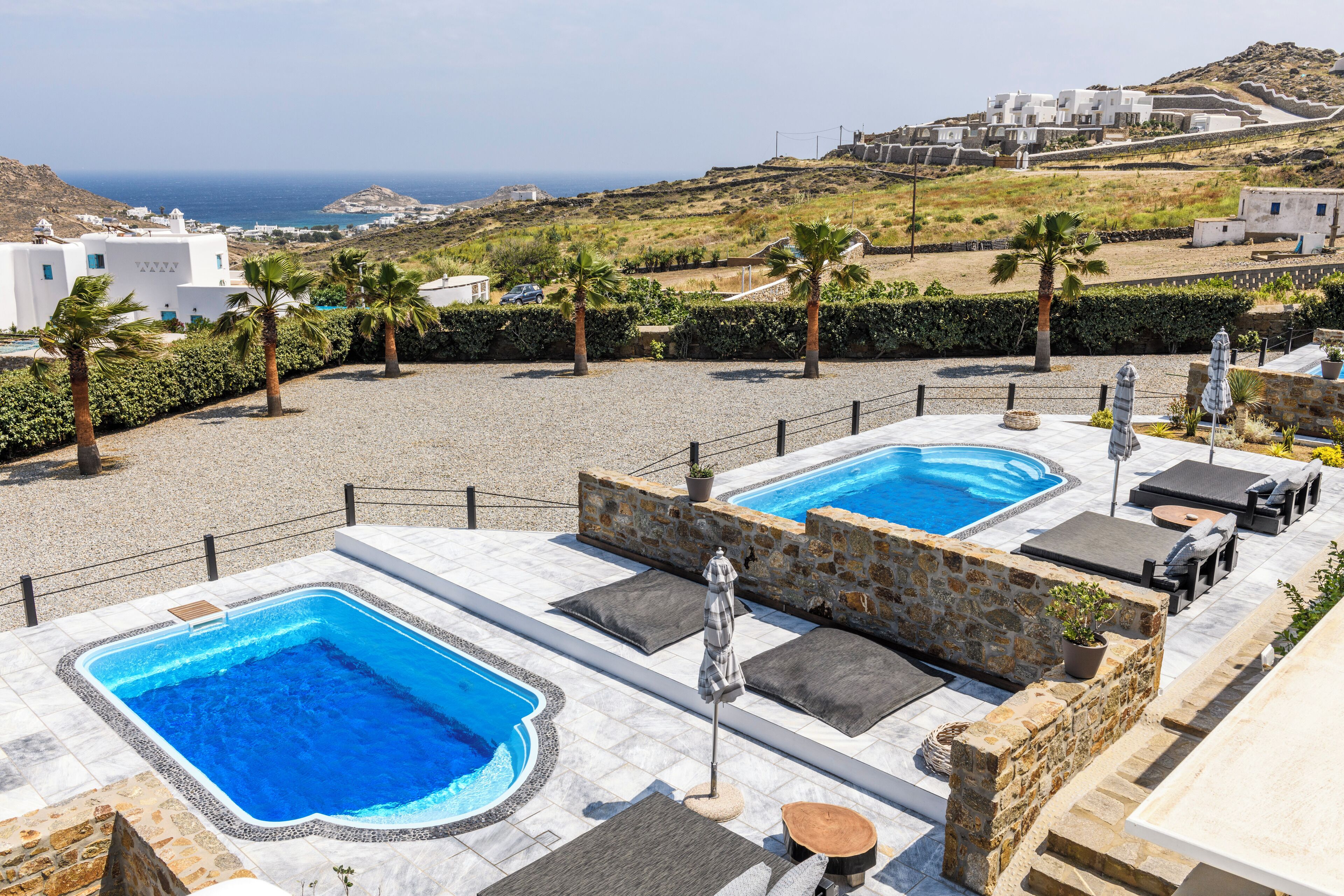 Un espace piscine sur le toit, comprenant deux piscines, des sièges extérieurs et une vue sur la côte.