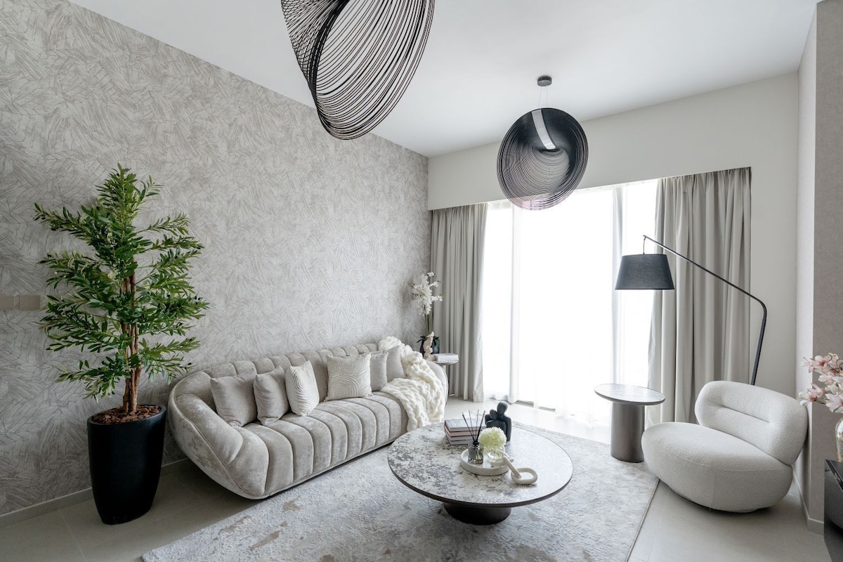 A modern living room with a sofa, a coffee table, a potted plant, and a floor lamp.