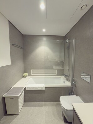 Une salle de bain moderne équipée d’une baignoire, de toilettes et d’un espace douche.
