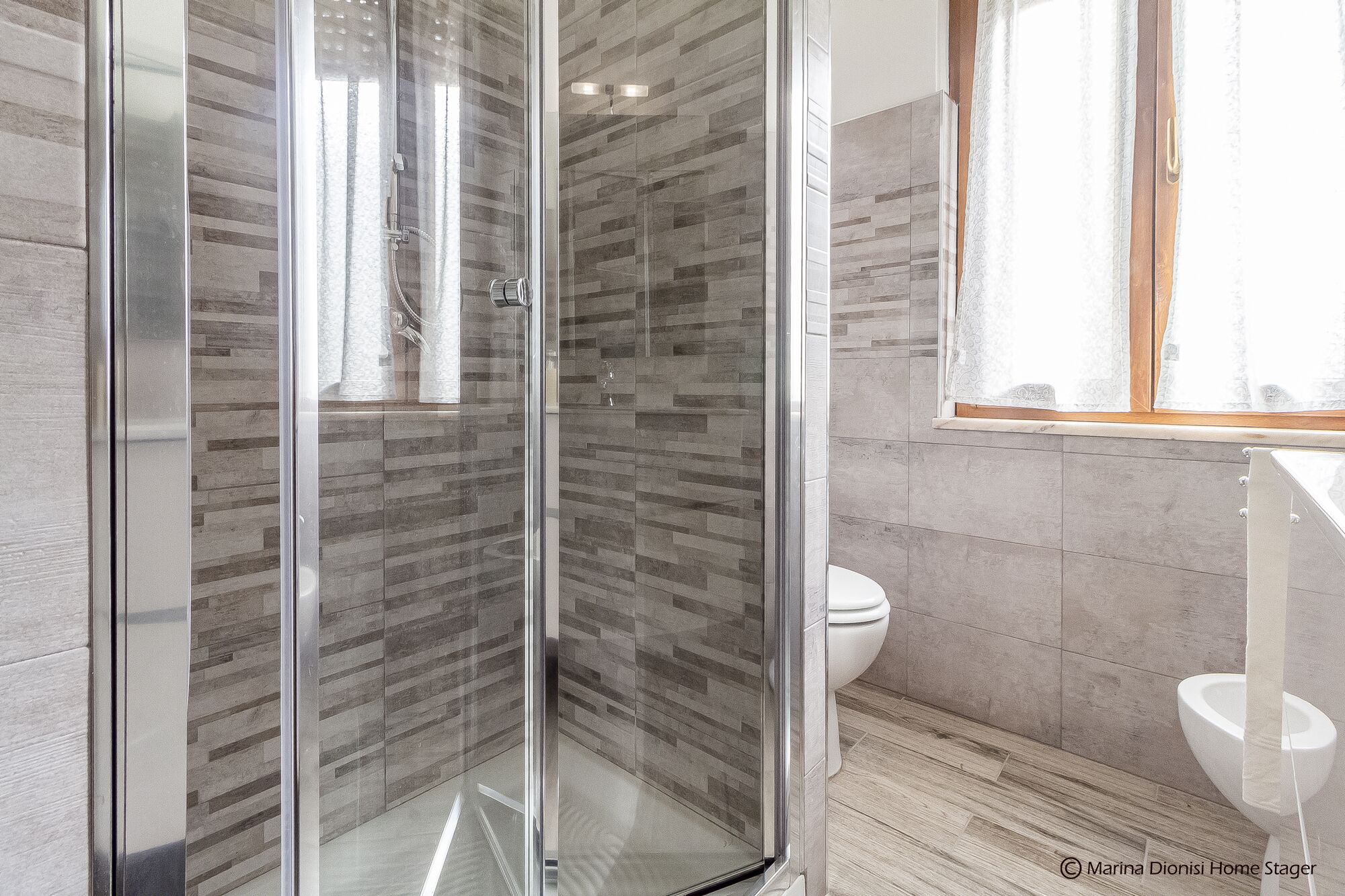 Een moderne badkamer met een douchecabine van glas, een toilet en een wastafel.