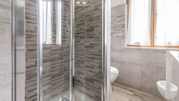 Een moderne badkamer met een douchecabine van glas, een toilet en een wastafel.