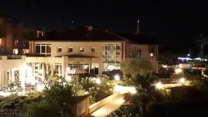 Moderni hotelli, jossa on tilava ulkoalue, jossa on uima-allas, aurinkotuoleja ja hyvin valaistu patio.