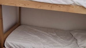 Ein Stockbett mit weißer Bettwäsche und einem Holz-Kopfteil.