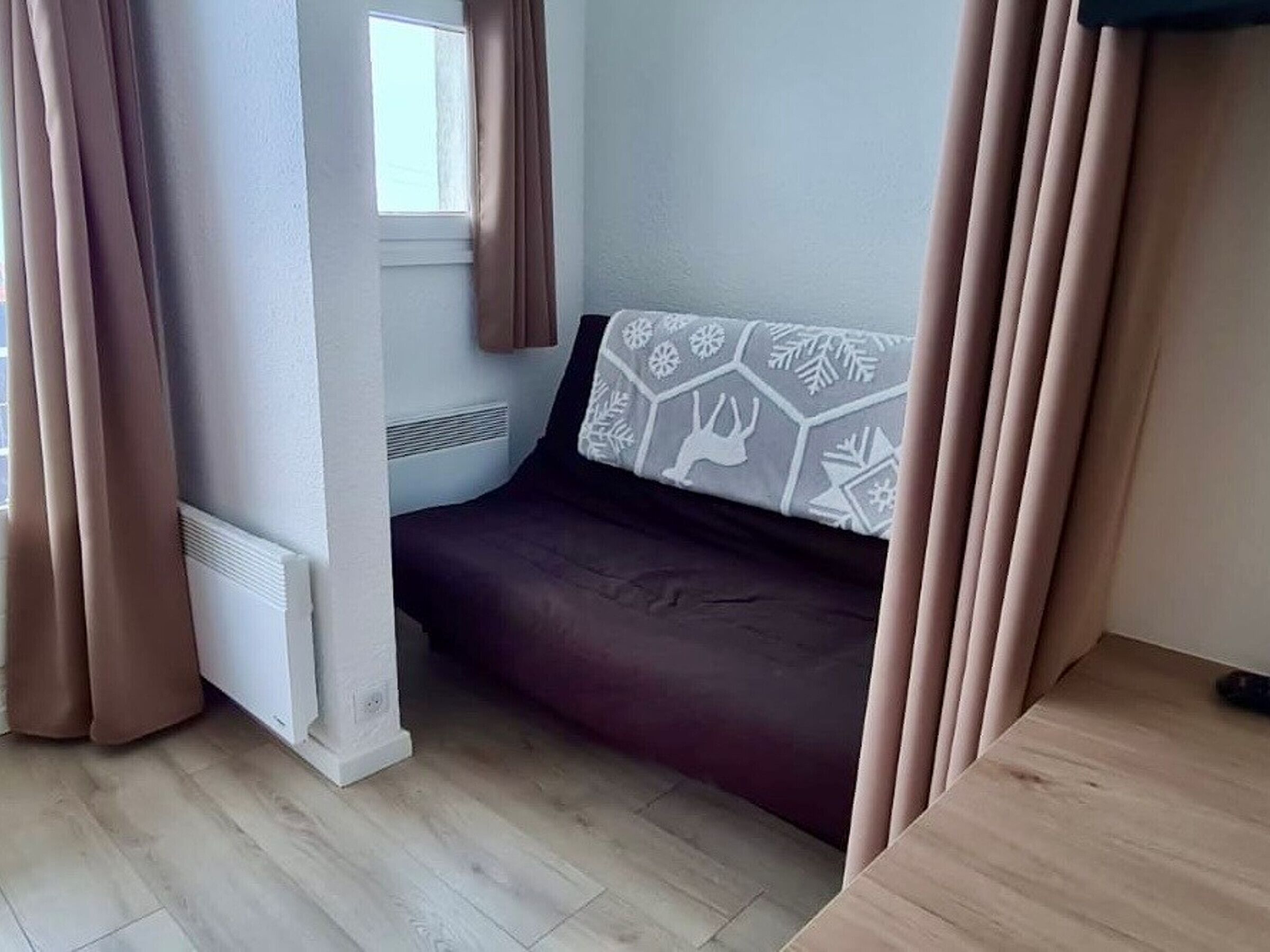 A small, cozy room with a bed, a window, and curtains.