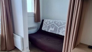 Ein kleines, gemütliches Zimmer mit einem Bett, einem Fenster und Vorhängen.
