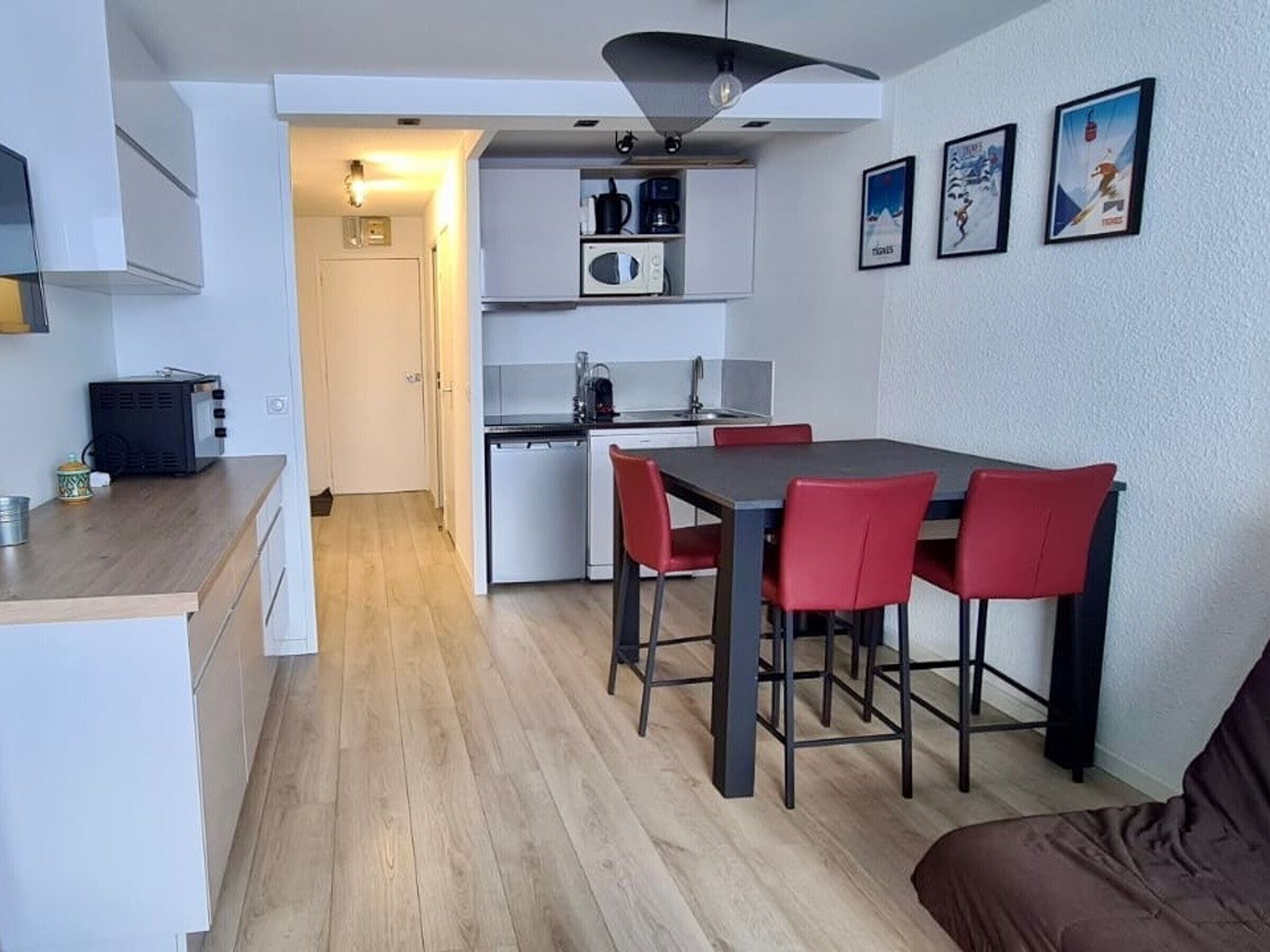 A compact kitchen with a dining area, a microwave, a coffee maker, and a small refrigerator.