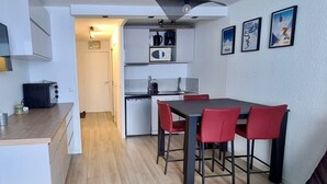 Eine kompakte Küche mit Essbereich, einer Mikrowelle, einer Kaffeemaschine und einem kleinen Kühlschrank.