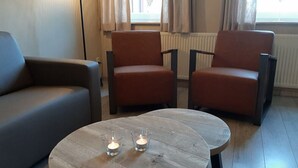 A modern living room with a sofa, two armchairs, and a coffee table with candles. - Vakantieboerderij Tergracht - t Huuske (Epen)
