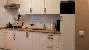 A kitchen with white cabinets, a sink, a stove, and a coffee maker. - Vakantieboerderij Tergracht - t Huuske (Epen)