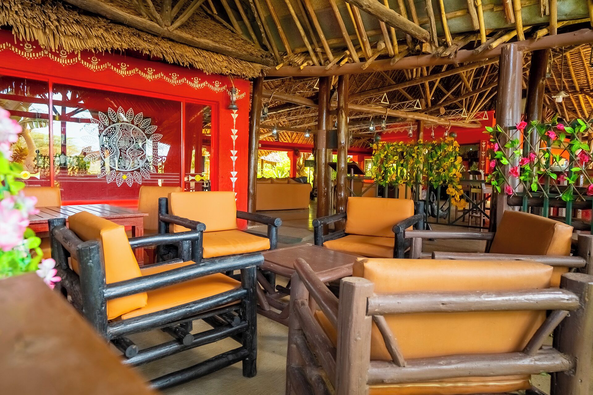 Un restaurante con mobiliario de madera y techo de paja.