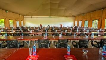 Un amplio salón de conferencias con filas de mesas y sillas, cada conjunto con botellas de agua y vasos.