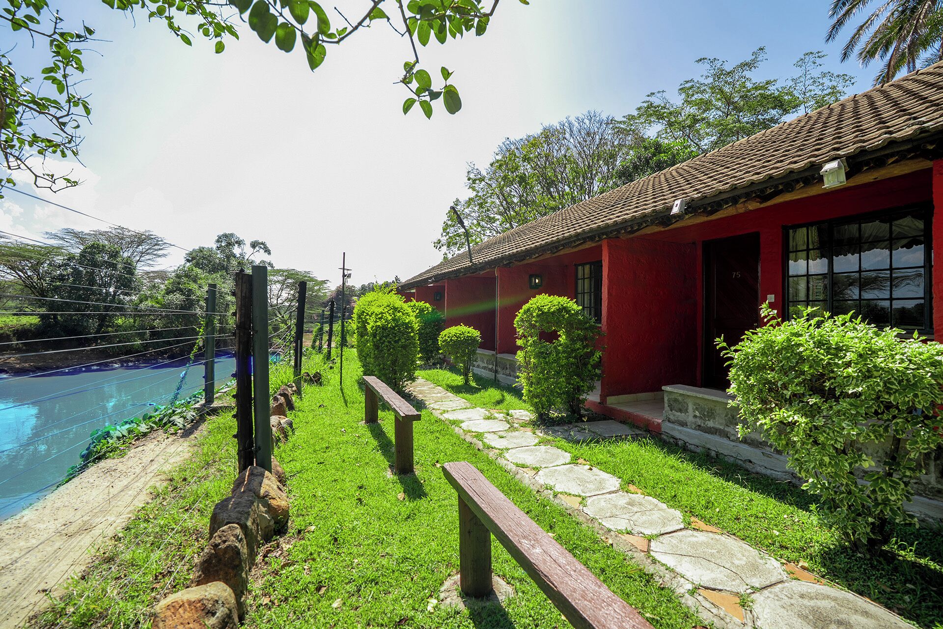 Un edificio rojo con techo de tejas, un camino de piedra y una piscina.