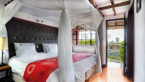 A bedroom with a four-poster bed, a nightstand, and a view of a garden through a window.