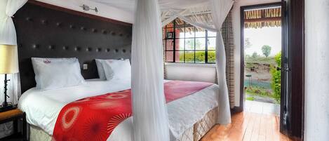 Un dormitorio con cama con dosel, una mesita de noche y vista a un jardín a través de una ventana.
