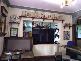 Um quarto com televisão, sofá, uma mesinha e uma estante com troféus.
