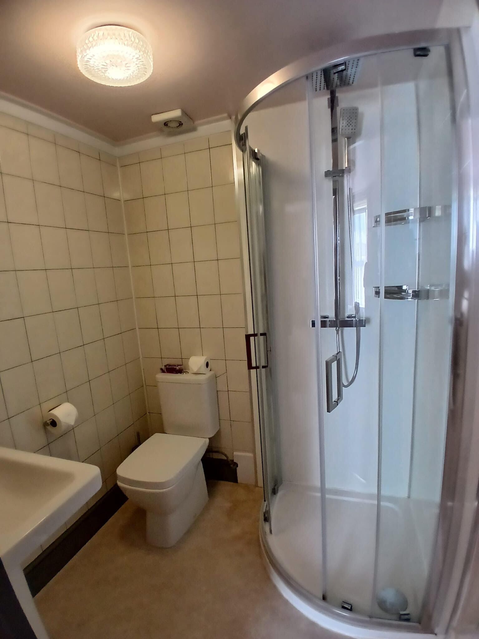 Un baño con inodoro, bañera y ducha con mampara de vidrio.