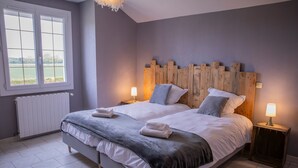 Quarto com cama grande, duas mesas de cabeceira com luminárias, vista pela janela e radiador.