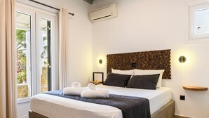 Un letto rifatto con biancheria bianca e scura, una testiera in legno e due lampade ai comodini.