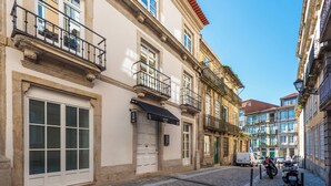 Une rue bordée de bâtiments historiques, un fourgon blanc et des motos garées.