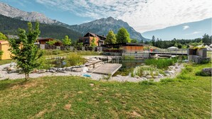 A lakeside cabin with a wooden deck, a small dock, and a mountain backdrop. - Sonnenplateau Cabins by amii (Wildermieming)