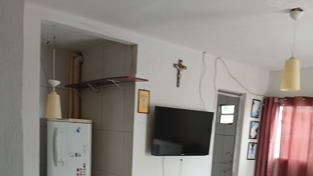 Un dormitorio con cama, televisión, refrigerador y puerta al baño.