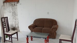 Una habitación con un sofá marrón, una mesa de vidrio y dos sillas de madera.