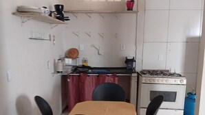 Una cocina pequeña con una mesa, sillas, estufa y lavamanos.