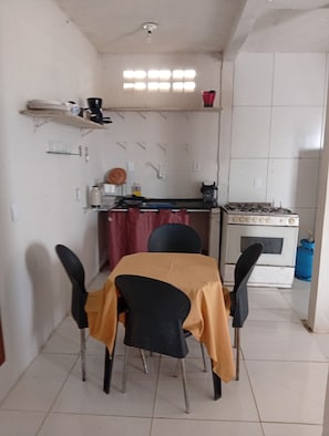 Uma cozinha pequena com mesa e cadeiras, fogão e pia.