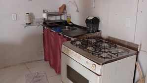 A compact kitchen with a gas stove, a sink, and a small countertop. - Lar Jampa Praias Sul (Conde)
