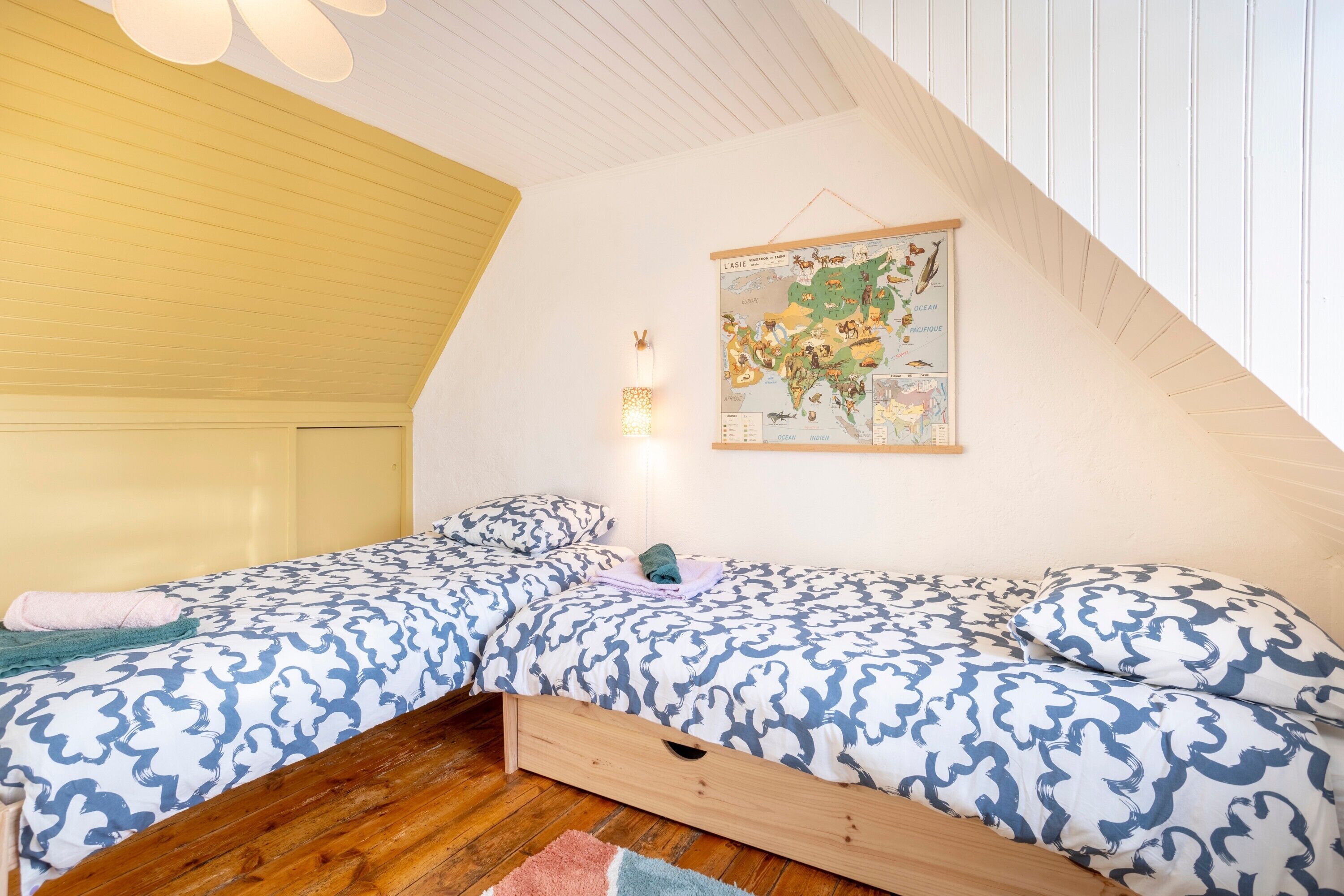 Une chambre avec deux lits, une carte accrochée au mur et un plafond en bois.