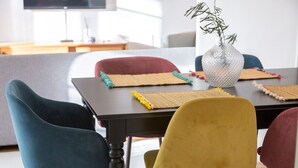 Une table à manger agrémentée d’un vase, de sets de table colorés et de chaises modernes.