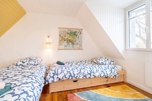 Ein Schlafzimmer mit zwei Betten, einer Weltkarte an der Wand und einem Fenster mit Blick.