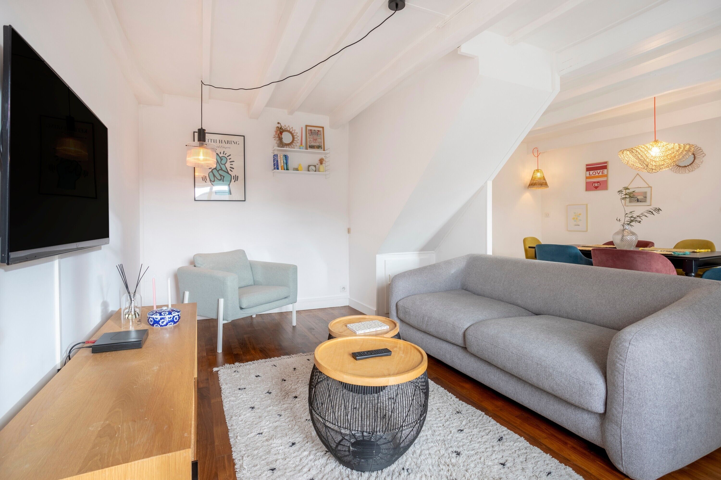 Una sala de estar moderna con un sofá gris, una mesa de centro de madera y un televisor montado en la pared.