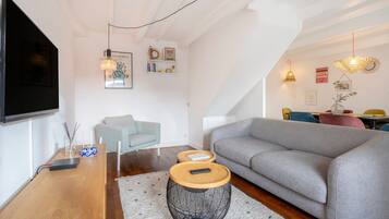 Una sala de estar moderna con un sofá gris, una mesa de centro de madera y un televisor montado en la pared.