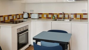 A modern kitchen with white cabinets, a microwave, an oven, and a dining area with a table and chairs. - Appartement rue Montorgueil au Halles - Paris 1 (Paris)