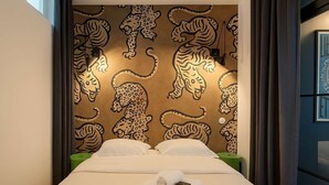A hotel room with a bed, a wall with a leopard print design, and a nightstand with a lamp. - Appartement rue Montorgueil au Halles - Paris 1 (Paris)