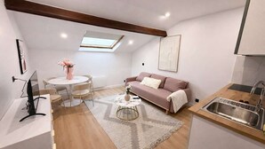 Un espacio habitable compacto con comedor, sofá, cocina con fregadero y tragaluz.