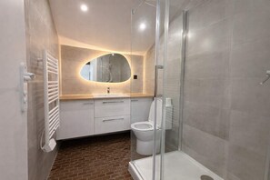 A modern bathroom with a glass shower enclosure, a white toilet, and a vanity with a mirror. - Sejour familial spacieux a Aubervilliers pour 4 (Aubervilliers)
