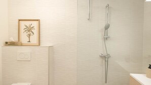 Un baño moderno con ducha, inodoro y lavamanos.